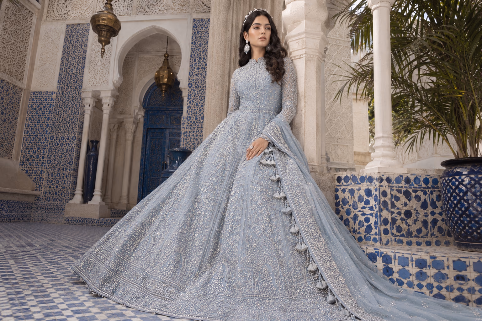 Wide editorial composition of the fashion model seated in a courtyard